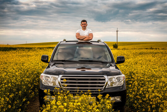 Young Man Standing In The Hatch Of A Car