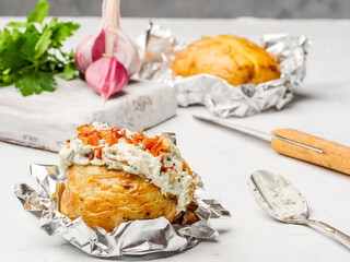 Potatoes baked in foil with cream cheese filling lie on the table.