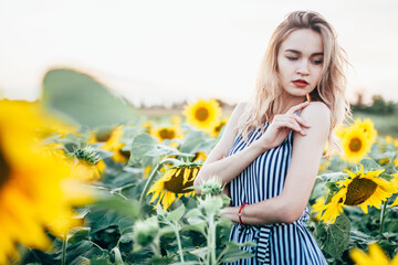 A young girl in a shirt stands in sunflowers