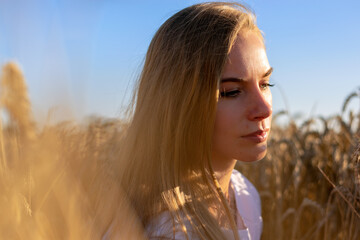 Young lady sitting at the wheat-land in a sunny day