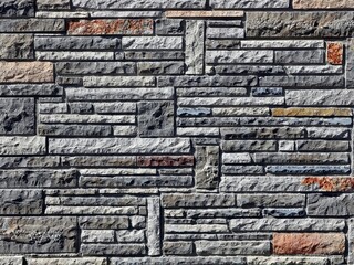 Exterior wall made of granite stones geometrically arranged. Background and texture.
