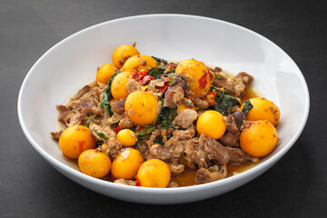 hot and spicy stir fried chicken ovary egg with chicken entrails and basil on dark grey texture background with copy space, Thai local street food