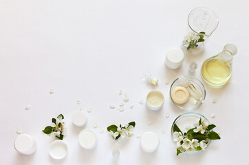 Natural cosmetics with floral apple extract. Jars of face and hand creams, soap and moisturizing gel on a laboratory table with chemical glassware. Creation of new types of cosmetics