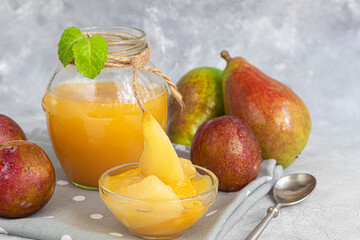 Plum jam. With the addition of pear slices. Purchase of products for future use. Fresh fruits in the background. On a gray background.