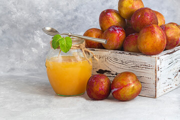 Plum jam. With the addition of pear slices. Purchase of products for future use. Fresh fruits in the background. On a gray background.
