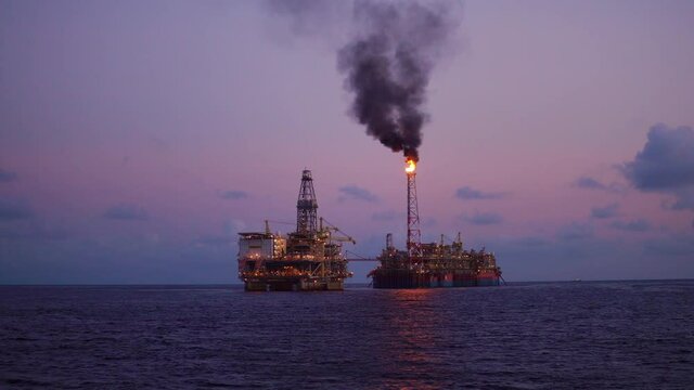 FPSO tanker vessel near Oil Rig platform. Offshore oil and gas industry. Flare is burning with smoke. Environmental pollution. 4k shot