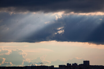 Naklejka premium Rays in black clouds . Stormy weather in the city 