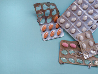 Pills inside medicine pack on blue background. Blister strip pack of pills and tablets in use packaging. Copy space.