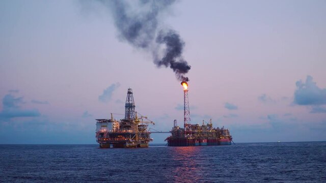 FPSO tanker vessel near Oil Rig platform. Offshore oil and gas industry. Flare is burning with smoke. Environmental pollution. 4k shot