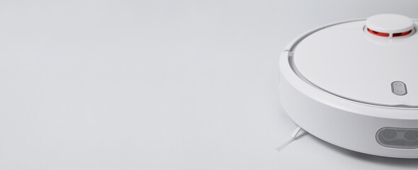 Modern robot vacuum cleaner on gray background flat lay. New technologies, quick house cleaning, automatic robot assistant. Free time to relax. Future technology, smart appliance for cleaning house