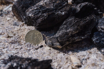 Russian coin lie on black hot coal among the ashes. One rubles in fire. Russian currency devaluated, finance and business concept