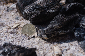 Russian coin lie on black hot coal among the ashes. One rubles in fire. Russian currency devaluated, finance and business concept