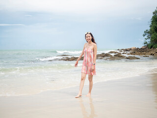 Fototapeta na wymiar asian woman in pink dress walking on beautiful beach at Samed, Thailand.