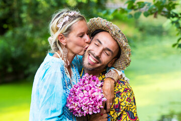 Fototapeta premium blond woman in blue dress kissing handsome man outdoors in nature