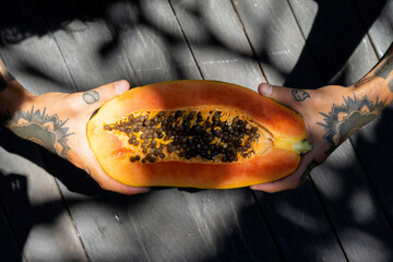 tropical fruits, papaya in hands with tattoos.