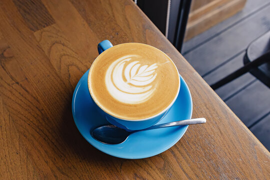Blue cup of fresh cappuccino with latte art