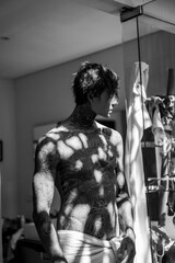handsome young man in tattoos in the bathroom after a shower in a towel.