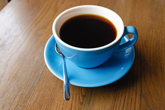 Blue cup with black coffee on the wooden table