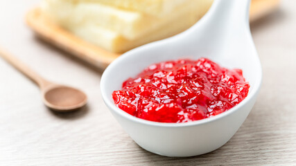 Strawberry Jam in white ceramic cup placed on wooden table. Food close up