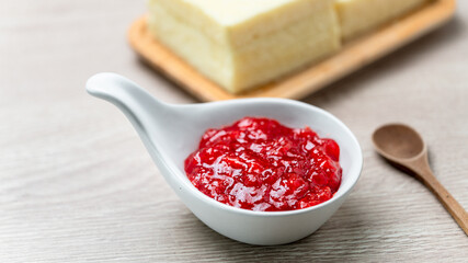 Strawberry Jam in white ceramic cup placed on wooden table. Food close up