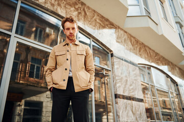 Elegant young man in formal classy clothes outdoors in the city near building