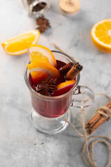 Mulled wine with slice of orange and spices on a gray concrete background