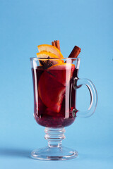 Mulled wine with slice of orange and spices on a blue background