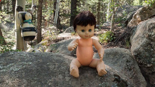 Cute Or Creepy Baby Doll Sitting On A Rock Without Clothes.