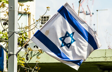 Flag of Israel waving in the center of Tel Aviv, Israel. blue Magen David sign and two stripes on white