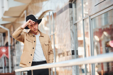 Fototapeta premium Elegant young man in black hat and formal classy clothes outdoors in the city