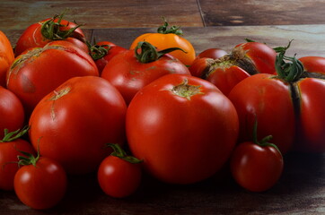 Abundance ripe organic tomatoes on dark rustic background. Colorful tomatoes 