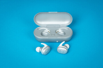 Wwireless bluetooth headphones on blue background. Modern wireless earphones