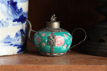 An antique teapot on a wooden counter.
