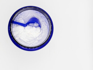Top view of a blue container containing a white powdered sports supplement with a blue scoop