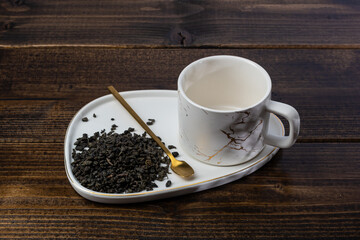 loose tea in a saucer next to a mug on a wooden background with different lighting