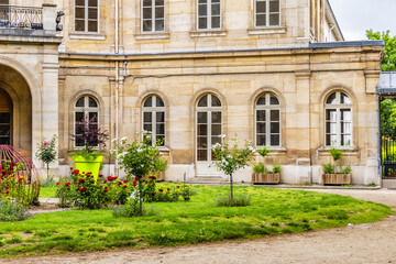 Fototapeta na wymiar Eugene-Napoleon building (1856) in little green Paris Public Park Jardin Eugene-Napoleon. Paris, France. [Inscription: Eugene Napoleon House built in 1856 by his majesty Empress].