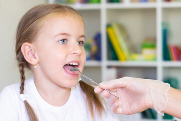 Speech therapy massage of the girl's tongue. a speech therapist makes a tongue massage to a child with a staging probe.