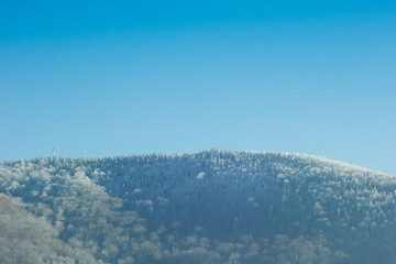 The mountain is covered with snow on a blue sky background