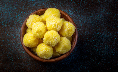 saffron flavoured desiccated coconut ladoo in a wooden bowl