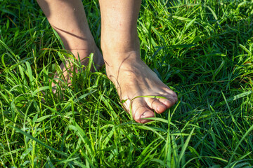 A man walks barefoot on the green grass in the morning
