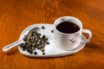loose tea in a saucer next to a mug on a wooden background with different lighting