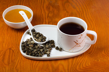 loose tea into the saucer next to the cup and sweets on the wooden background with different lighting