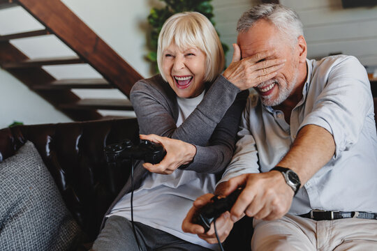 Couple Of Caucasian Retired Seniors Playing Video Games Together At Home