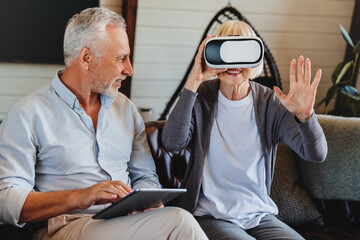 Old elderly retired woman using VR virtual reality headset in apartment.