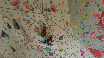 AERIAL: Athletic girl prepares for a climbing competition by training indoors.
