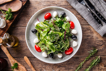 Salad with greens mozzarella olives and tomatoes