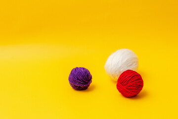 Obraz na płótnie Canvas white, red and blue balls of wool lie on a yellow background