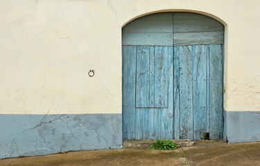 An old blue wooden door and a ring to tie the horses to the wall next to it.