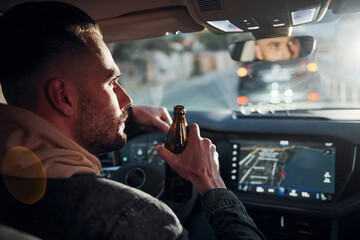 Dont drink and drive. Rear view of handsome unshaved man in fashionable clothes inside his automobile