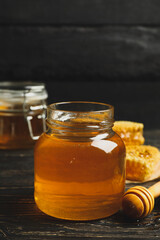 Honeycombs, jar with honey and dipper on wooden background